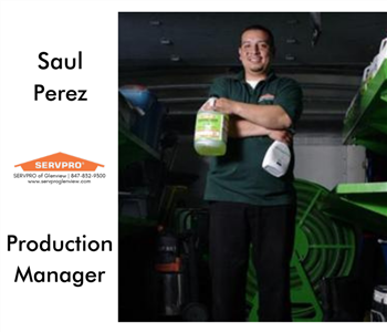 Male employee standing in our work truck, holding SERVPRO product bottles in hands, arms crossed, smiling